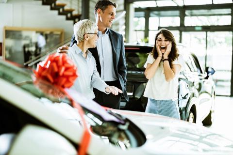 Three people in a car showroom.